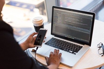 Person am Handy und Laptop zugleich